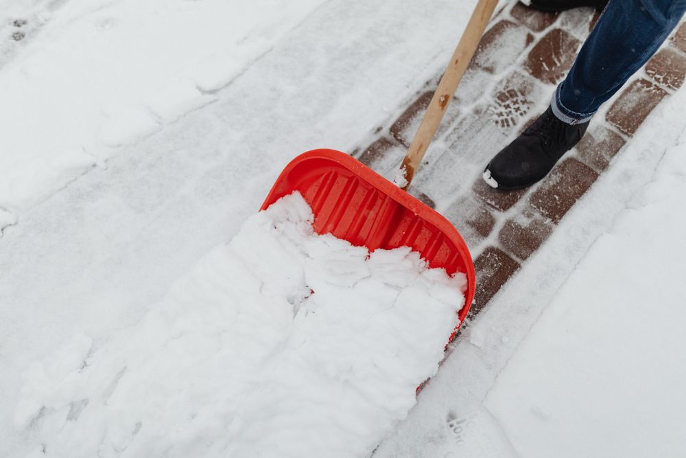 Stock photo of a walkway being cleared with a snow shovel